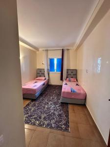zwei Betten in einem Zimmer mit Fenster in der Unterkunft 213 mdiq Appartement parfait à louer à kabila vista 2 chambre salon piscine 2 balcon 90 mètres carré in Marina Smir