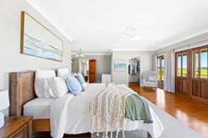 a white bedroom with a bed and a living room at 58 Mystery Bay Road, Mystery Bay in Central Tilba