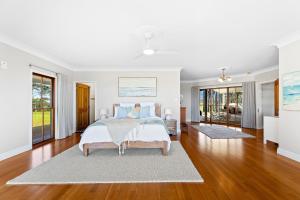 a white bedroom with a bed and wooden floors at 58 Mystery Bay Road, Mystery Bay in Central Tilba