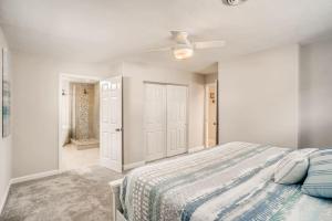 a white bedroom with a bed and a ceiling fan at Between the Waves Cottage by the Sea in Ormond Beach