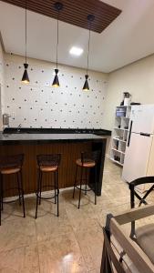 a kitchen with a bar with chairs and a refrigerator at Casinha da Ana in Bacabal +7 photos