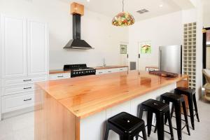 una cucina con piano di lavoro in legno e sgabelli neri di 'Braeside'- Victoria St's Secret ad Albury