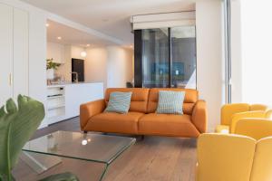 an orange couch and chairs in a living room at Prime CBD central 3bedroom apartment in Canberra