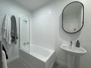 a white bathroom with a sink and a mirror at Discerning in Thorndon in Wellington
