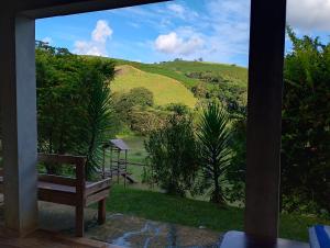 Una vista de una colina desde un porche con un banco. en Chácara bela vista, en Socorro