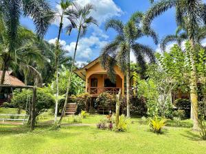 a house with palm trees in front of it at Khao Sok Nung House in Khao Sok National Park
