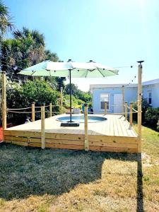 una terraza de madera con una sombrilla encima en Blowfish Bungalow-Cowboy Pool FirePit Ping Pong, en Daytona Beach