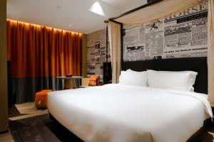 广州Arthur Hotel Baiyun Guangzhou的卧室里有一张白色的大床和一面报纸墙