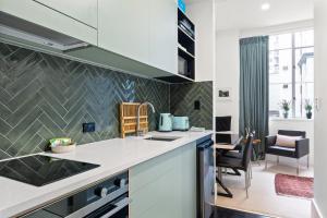 a kitchen with white countertops and a living room at slick city apartment in Auckland