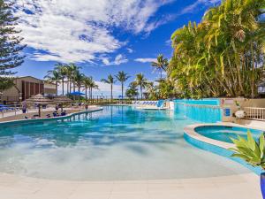 une grande piscine avec de l'eau bleue et des palmiers dans l'établissement Royal Palm Resort on the Beach, à Gold Coast