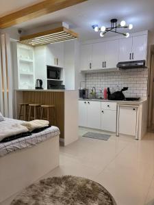 マニラにあるCozy Escape at The Avenueの白いキャビネットとソファ付きのキッチンが備わります。