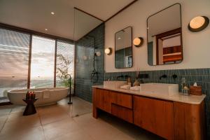a bathroom with two sinks and a tub and mirror at Grün Resort Uluwatu in Uluwatu