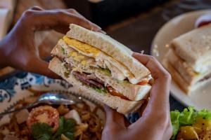 una persona che tiene in mano un panino davanti a un piatto di cibo di Golden Garuda Cottages at Diamond Beach Hills a Nusa Penida