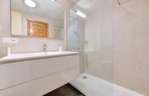 a white bathroom with a sink and a shower at Experience the running of the bulls from your balcony in Pamplona +17 photos