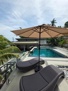 an umbrella and lounge chairs next to a swimming pool at Bulihan Suites Puerto Galera in Puerto Galera