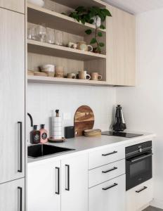 a kitchen with white cabinets and a sink at Modern Studio with Outdoor Bath and Cabin Sauna in Albion Park