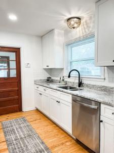 Una cocina con gabinetes blancos y un fregadero y una ventana. en Changes In Latitude Pet Friendly Retreat, en Daytona Beach