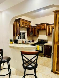 a kitchen with wooden cabinets and two chairs in it at Olive Breeze II in Runaway Bay +10 photos