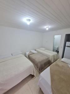 three beds in a room with white walls at Flat & Suíte Campos in Campos do Jordão