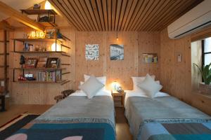 twee bedden in een kamer met houten wanden bij Batonship Inn Osaka 005 in Osaka