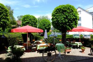 un jardín con mesas, sillas, sombrillas y una bicicleta en Hotel Löwen, en Kirchzarten
