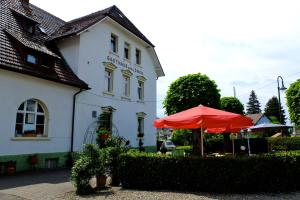 ein weißes Gebäude mit einem roten Regenschirm davor in der Unterkunft Hotel Löwen in Kirchzarten