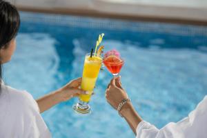 two people holding drinks in front of a pool at Hanoi Splendid Premium Hotel in Hanoi +85 photos
