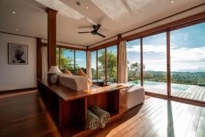 a bedroom with a bed and large glass windows at Grün Resort Uluwatu in Uluwatu