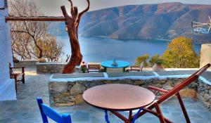 a table and chairs on a patio with a view of a lake at Pano Gitonia in Aegiali
