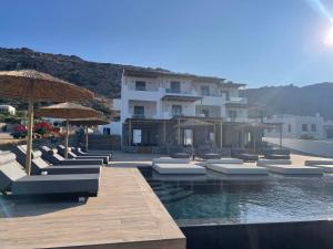 a pool with chairs and umbrellas and a building at Latramys Suites in Mikri Vigla