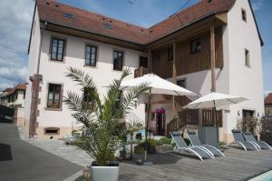 a building with chairs and umbrellas in front of it at Chambres d'h&ocirc;tes - L'Ecurie Obernai in Obernai