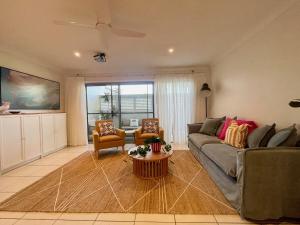 una sala de estar con un sofá y una mesa en Jetty Blonde - Bright, Beachy & Perfectly Located, en Coffs Harbour