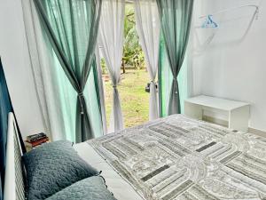 a bedroom with a bed and a window with curtains at EmbunSari Serimenanti Homestay 