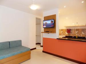 a room with a couch and a tv on a wall at Ancoradouro Flats in Abraão