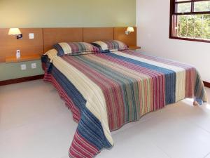 a bedroom with a large bed with a colorful blanket at Ancoradouro Flats in Abraão