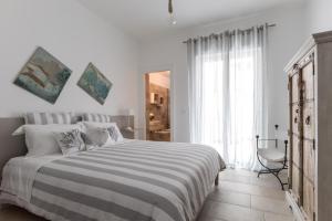 a white bedroom with a bed and a chair at Heima Mare in Isola delle Femmine