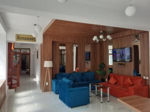 ein Wohnzimmer mit blauen und roten Sofas und einem Fernseher in der Unterkunft Hotel Gâlma in Moroeni