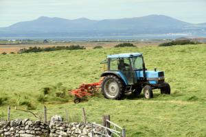 a blue tractor is sitting in a field at Ystumgwern Luxury Barn Conversions in Dyffryn