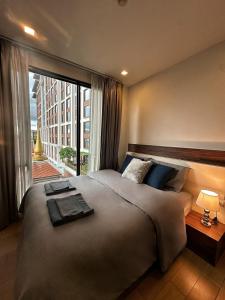 a bedroom with a large bed with a large window at The Astra Condo, Downtown in Chiang Mai