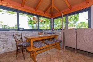 un patio con mesa de madera, sillas y ventanas en Villa Vita, a Lush Romantic Retreat in a private Forest, en Vinež
