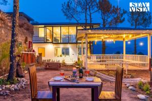 a table with wine glasses on it in front of a house at StayVista at Petal Perch 4 BR and 2 BR with Bonfire in Kasauli in Kasauli