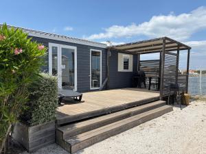 乐巴凯尔斯Azur Premium Climatisé 4 étoiles au camping la presqu'île du Barcarés vue imprenable的海滩上带木甲板的房子