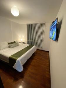 una camera da letto con un letto e una TV a muro di Modern Stylish - Exclusive area of Cochabamba a Cochabamba