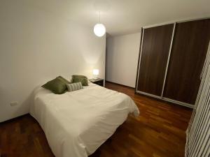 una camera da letto con un letto con lenzuola bianche e cuscini verdi di Modern Stylish - Exclusive area of Cochabamba a Cochabamba Altre 19 foto