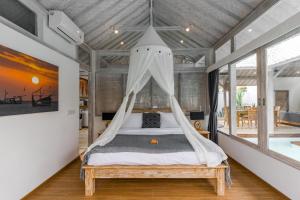 a bedroom with a bed with a mosquito net at Villa Cemacase - Stylish 2BR Villa with Spacious Private Pool & Pool Table in Seseh in Cemagi