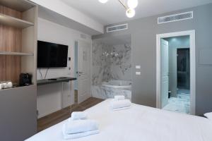 a white bathroom with a tub and a tv in a room at Maison Rasella Palace Suites in Rome +121 photos