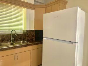a white refrigerator in a kitchen next to a sink at Pedros Heights in Tumon