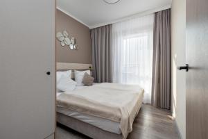 ミエンジズドロイェにあるMiedzyzdroje SEASIDE Apartments Bel Mare by Noclegi Rentersの白いベッドと窓のある寝室