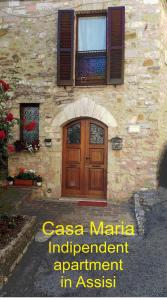 a stone building with a wooden door and a window at Casa Maria in Assisi