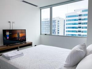 a bedroom with a bed with a flat screen tv at Suite de lujo cerca al aeropuerto, terminal, mall sol in Guayaquil